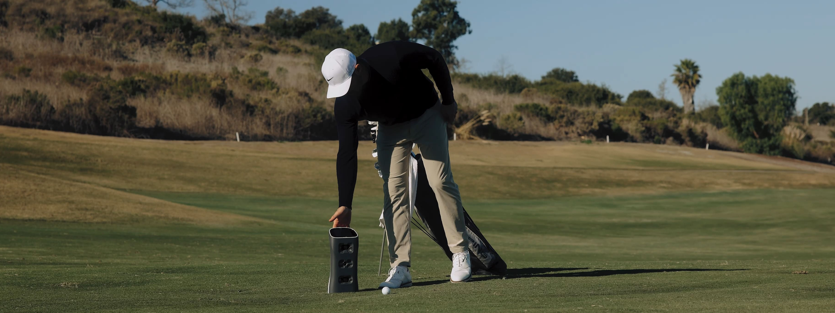 Person on a golf course preparing to hit a golf ball with GOLFJOY Spica 3.