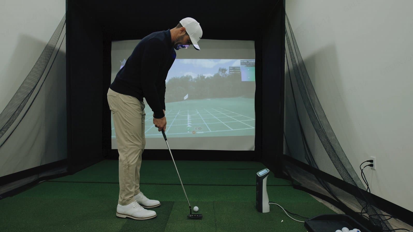 Golfer die binnen put met een draagbare GolfJoy Spica launch monitor